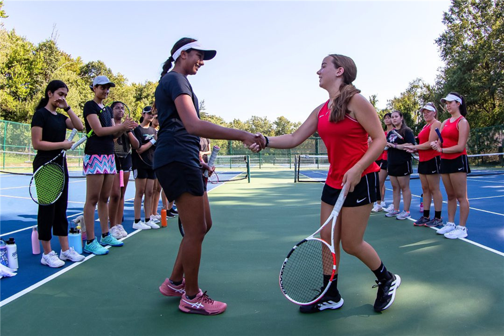 Students shake hands on tennis court.